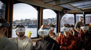 Bezoeker kijkt door een VR-bril tijdens een bijzondere boottocht op de Amsterdamse grachten